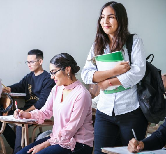 woman carrying white and green textbook